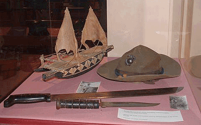 Marine hat, knife, and machete used by Ed Domagala in the South Pacific. Model of Islander boat