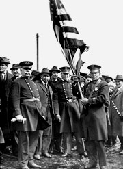 Chief William Brennan, Arnold Kurth holding the flag. Daniel Hanrahan next to Kurth, Frank B. Curley at extreme right. From other images it appears that this was at or before the 275th Anniversary Parade 1916. Stamford Historical Society.