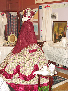 Back view of a fringed jacquard traveling mantle and bonnet with outer lace bavolet  at the nape.