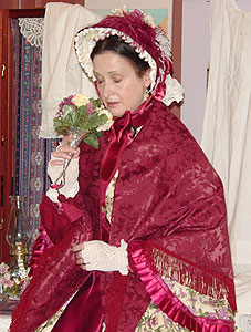 Front view of bonnet and traveling mantle with a cone shaped silver nose gay holder called a tussie mussie.